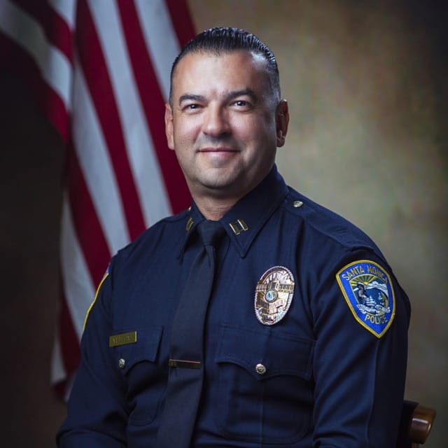 Police officer in formal uniform seated with an American flag in the background