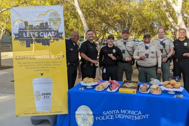 Santa Monica Police Department officers at a community event table with coffee, pastries, and a "Coffee with a Cop" sign.